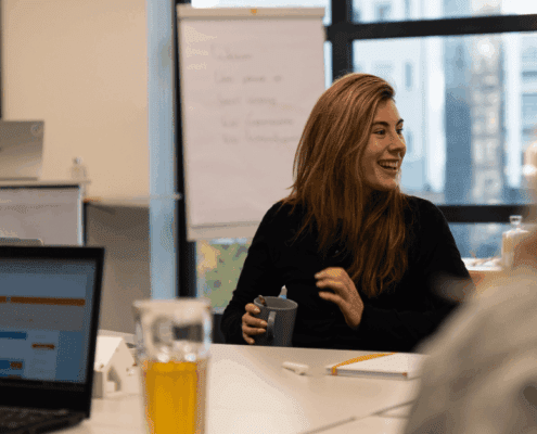 Vrouw aan tafel kijkt lachend naar rechts | AvA seminar GEO